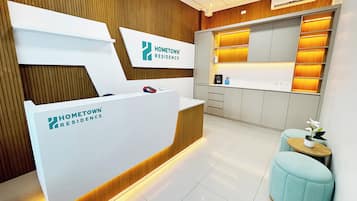 A reception area with a reception desk, a small seating area, and a kitchen area with cabinets and a countertop.