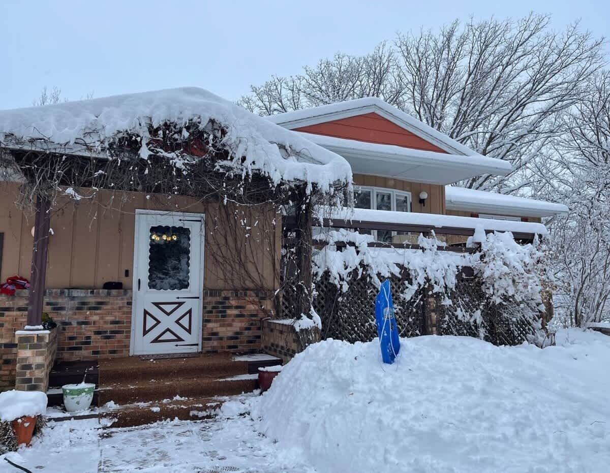 Une maison dont le toit est recouvert de neige et dont la façade est en briques.