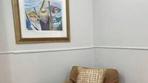 A small, single-room suite with a sofa bed, a small side table, and a framed picture on the wall.