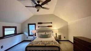 A bedroom with a bed, a ceiling fan, a window, and a nightstand. - The Stonefire Cabin! (Sparta Township)