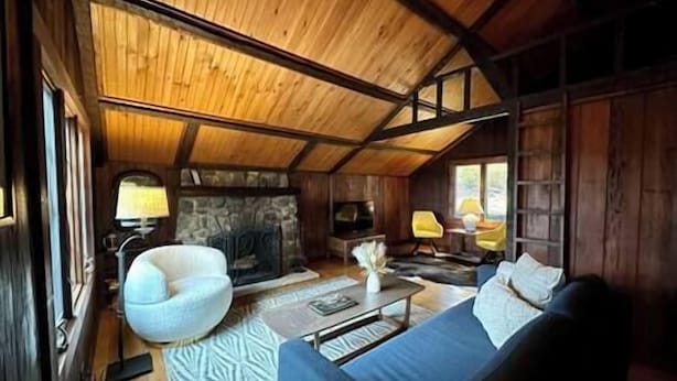A cozy cabin interior with a stone fireplace, a blue sofa, and a wooden ceiling. - The Stonefire Cabin! (Sparta Township)