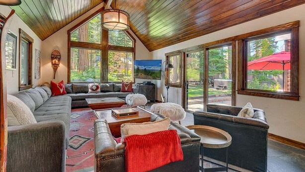 A spacious living room with a large sectional sofa, a coffee table, and a fireplace. Large windows provide views of the outdoors. - Finch Haven in Homewood (Homewood)