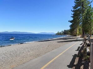 A coastal road with a paved path, a clear blue sky, and a body of water. - Finch Haven in Homewood (Homewood)