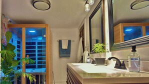 Ein Badezimmer mit Waschbecken, Spiegel, Handtuchhalter, Topfpflanze und Blick auf einen Balkon.