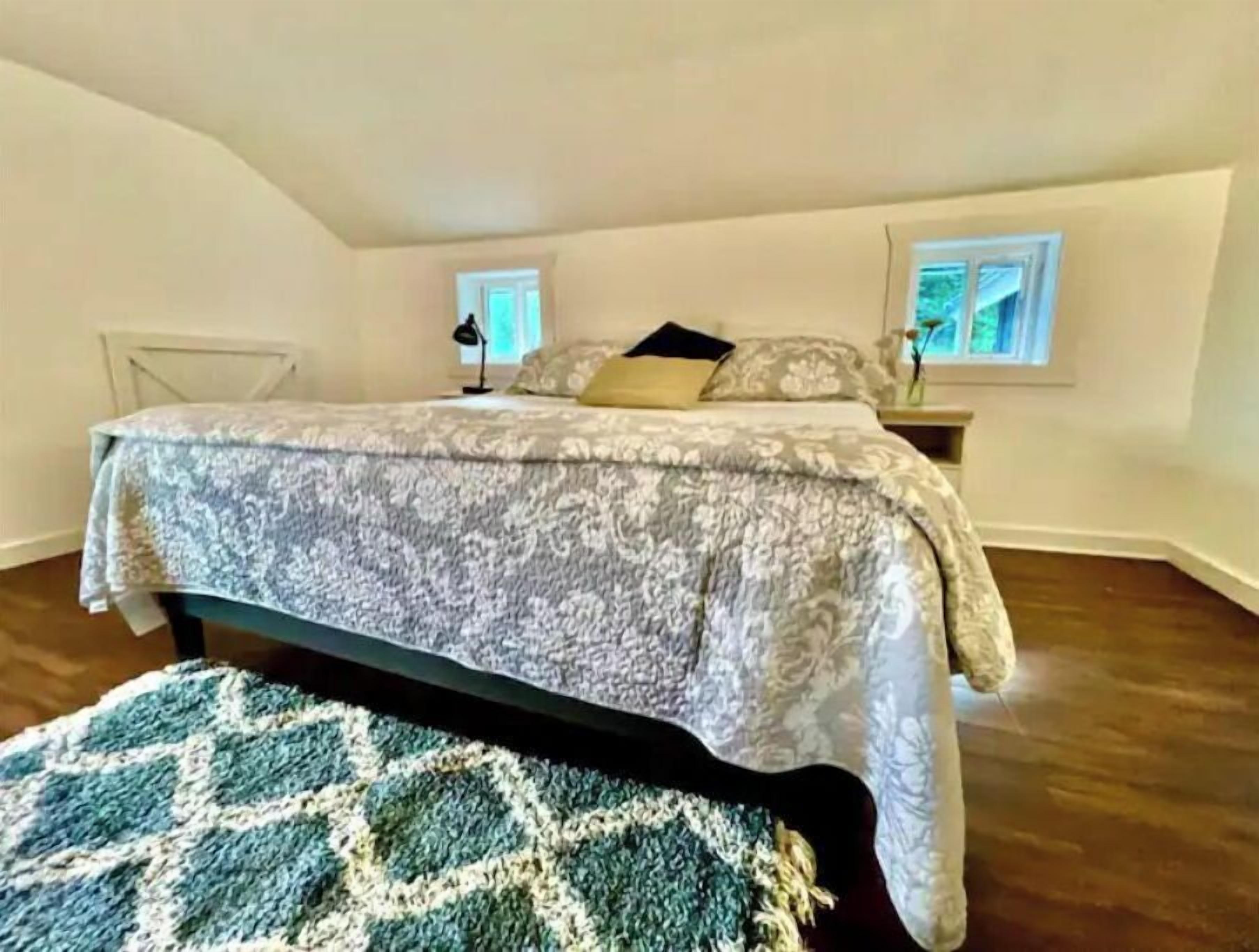 A bedroom with a bed, bedside tables, a window, and a patterned rug.
