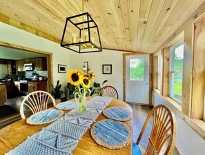 A dining area with a wooden table, woven placemats, and a geometric pendant light.