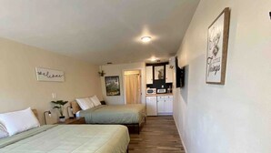 Une chambre avec deux lits, une kitchenette et une petite salle de bain.