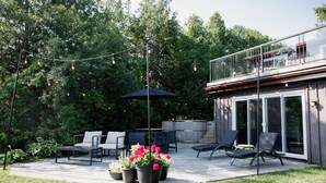 An outdoor patio with a dining table, chairs, and potted plants.