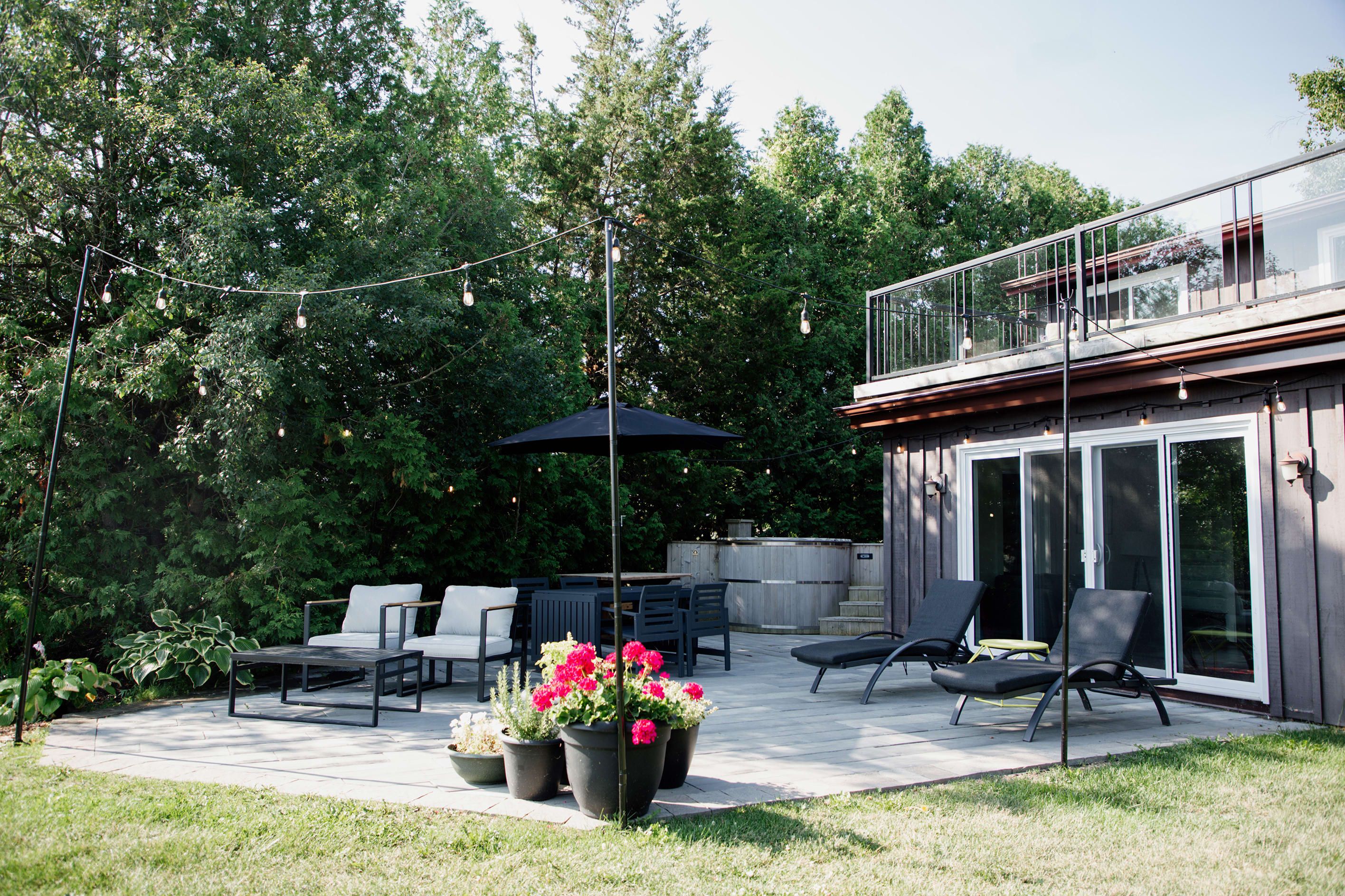 An outdoor patio with a dining table, chairs, and potted plants.
