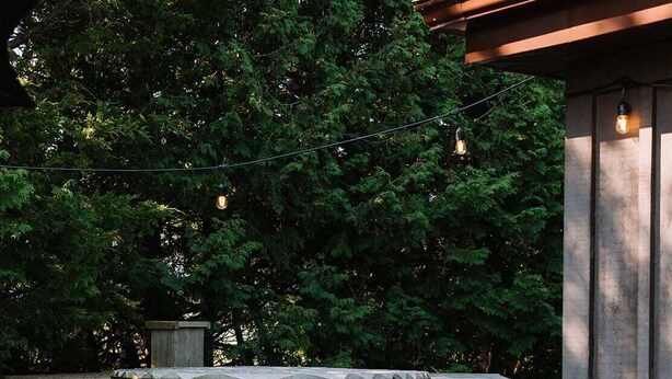 A wooden deck with a hot tub and steps leading up to it, surrounded by trees.