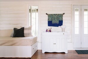 A room with a white sofa, a white cabinet, and a patterned tapestry.