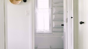 A hallway with a wooden floor, a white door, and a window with a view of a white closet.