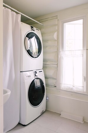 A laundry area with two stacked washing machines and a window with a view of the outdoors.