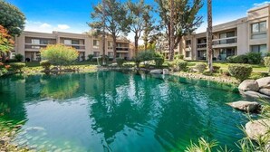 A hotel courtyard with a clear blue pool surrounded by trees and a well-maintained garden. - Canyon Shores Desert Escape! (Cathedral City)