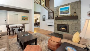 A spacious living area with a fireplace, a dining area, and a staircase leading to an upper level. - MEAD75 - Updated Home with AC, Bikes, Pet-Friendly (Sunriver)