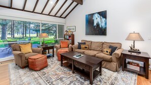 A living room with a large window, a brown sofa set, a coffee table, and a patterned rug. - MEAD75 - Updated Home with AC, Bikes, Pet-Friendly (Sunriver)