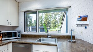 A modern kitchen with a stainless steel sink, a built-in microwave, and white cabinetry. - MEAD75 - Updated Home with AC, Bikes, Pet-Friendly (Sunriver)