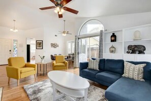A spacious living room with a blue sofa, yellow armchairs, a white coffee table, and a ceiling fan. - Vibrant home with gazebo (Sacramento)
