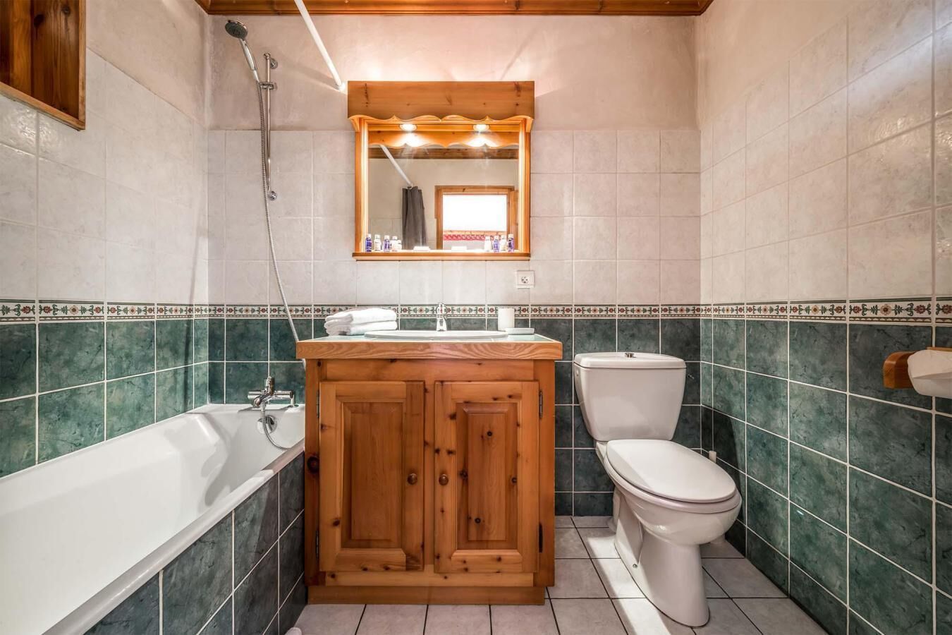 A bathroom with a wooden vanity, a bathtub, and a toilet.