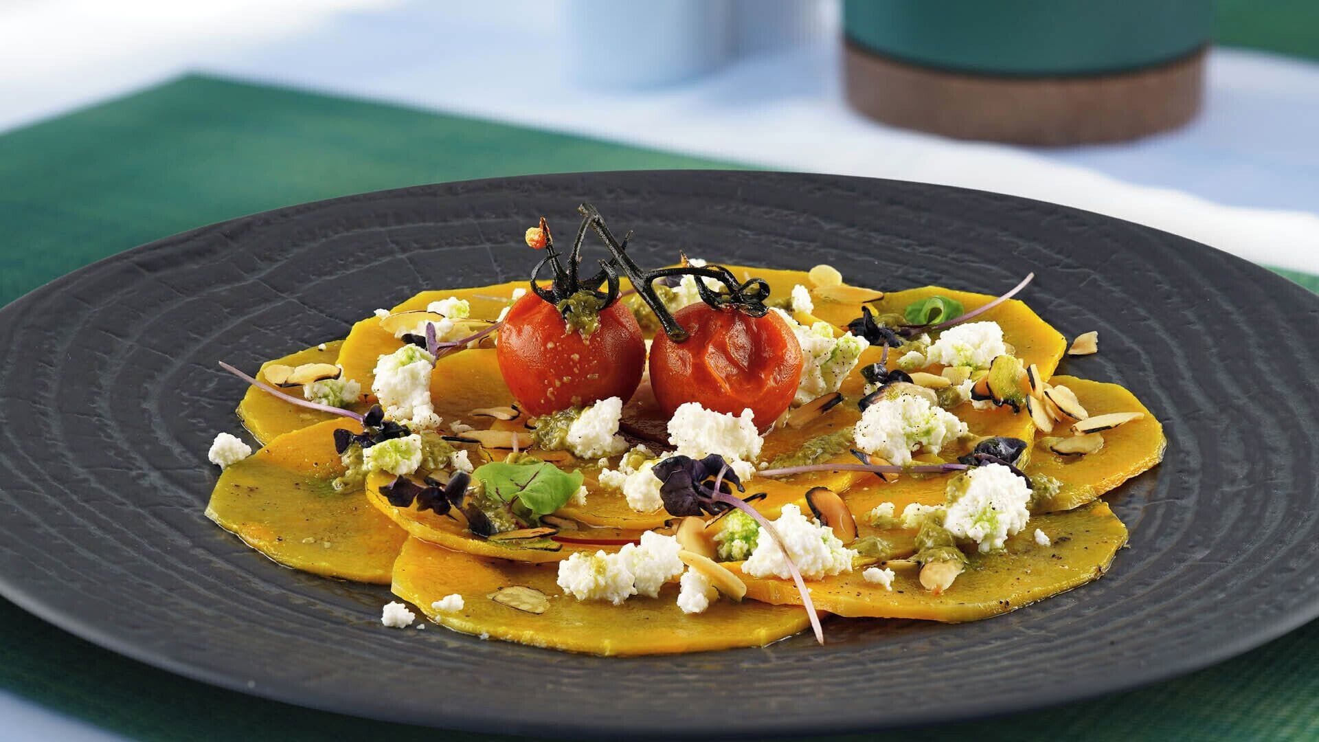 A plate of food with tomatoes, cheese, and greens on a dark plate.