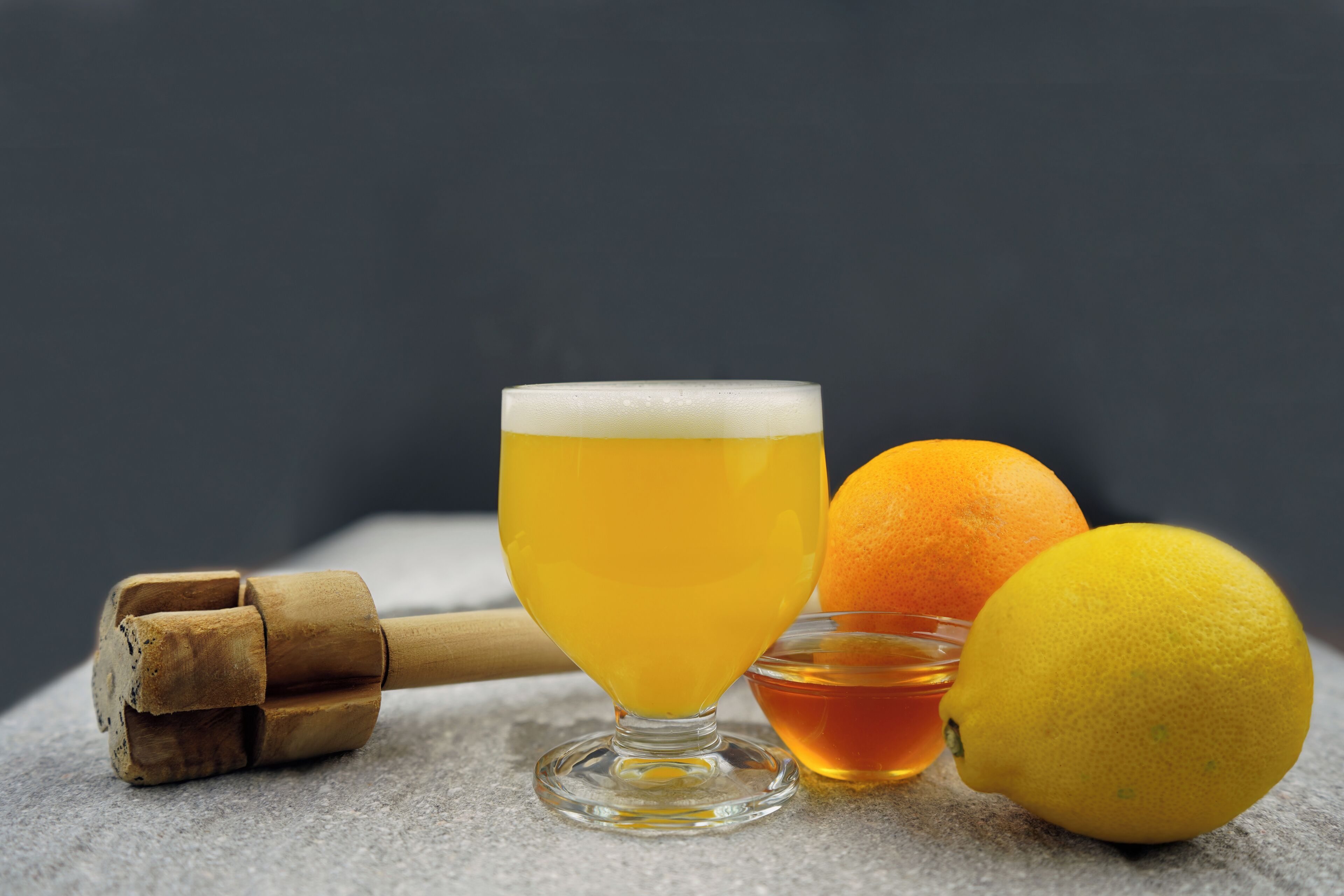 Een glas bier, een sinaasappel en een citroen op een stenen ondergrond.