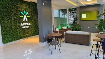 Eine moderne Hotelhalle mit einer grünen Wand, einer Rezeption und Sitzbereichen.