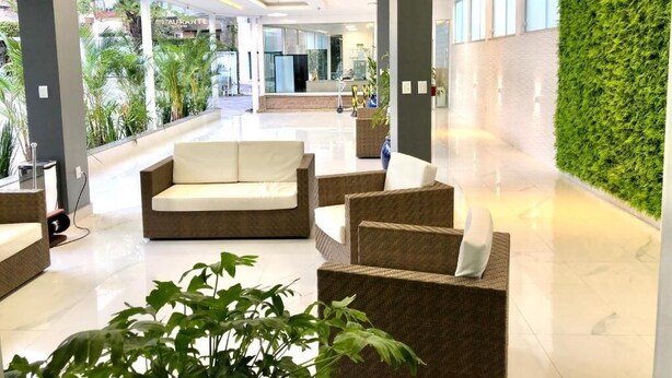 A modern lobby with a green wall, seating area, and a view of the outside. - HOTEL APPEL (Santa Maria)