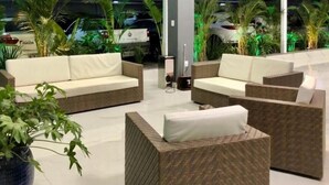 A modern outdoor seating area with wicker furniture and potted plants. - HOTEL APPEL (Santa Maria)