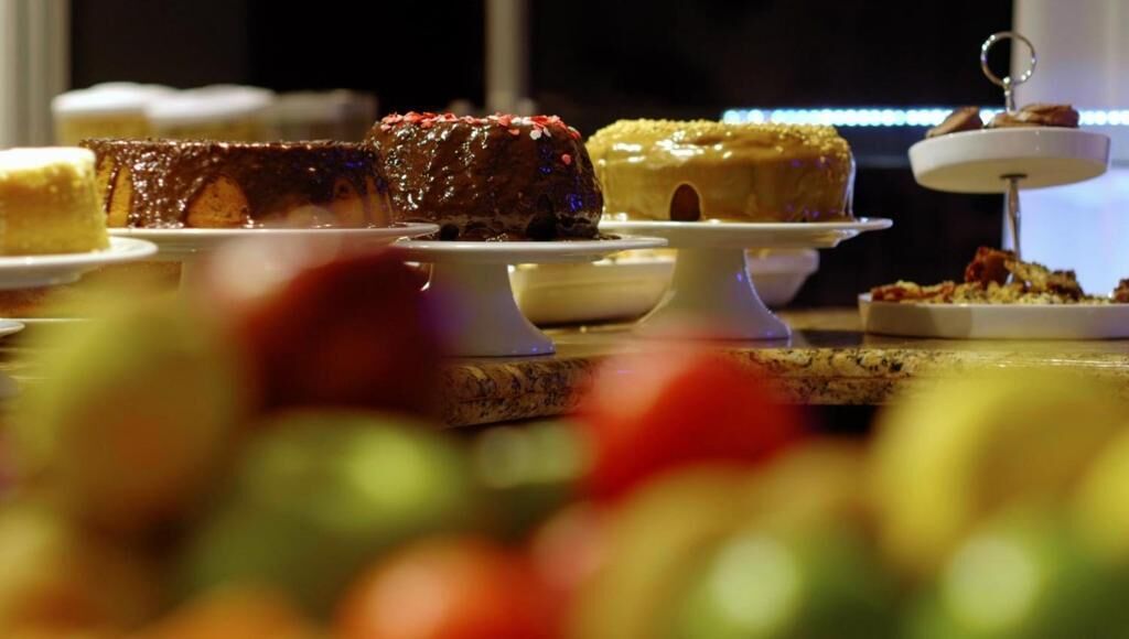 A dessert display with various cakes and pastries on white stands.
