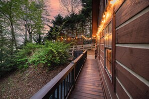 A wooden deck with a railing, surrounded by greenery and trees, leading to a building with windows. - ⭐️ Mountain view • hot tub • game table • dogs welcome ⭐️ (Blue Ridge)