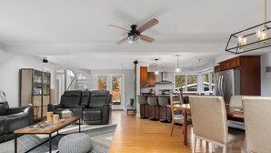 A modern living room with a sofa, coffee table, and a dining area with chairs. - Wooded & Quiet, but Downtown. Spacious Home w/ Smokeless Fire Pit, Barrel Sauna (Bellaire)
