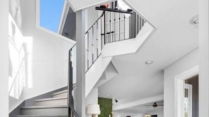 A modern interior with a spiral staircase, a living area with a sofa and a coffee table, and a green wall accent. - Wooded & Quiet, but Downtown. Spacious Home w/ Smokeless Fire Pit, Barrel Sauna (Bellaire)