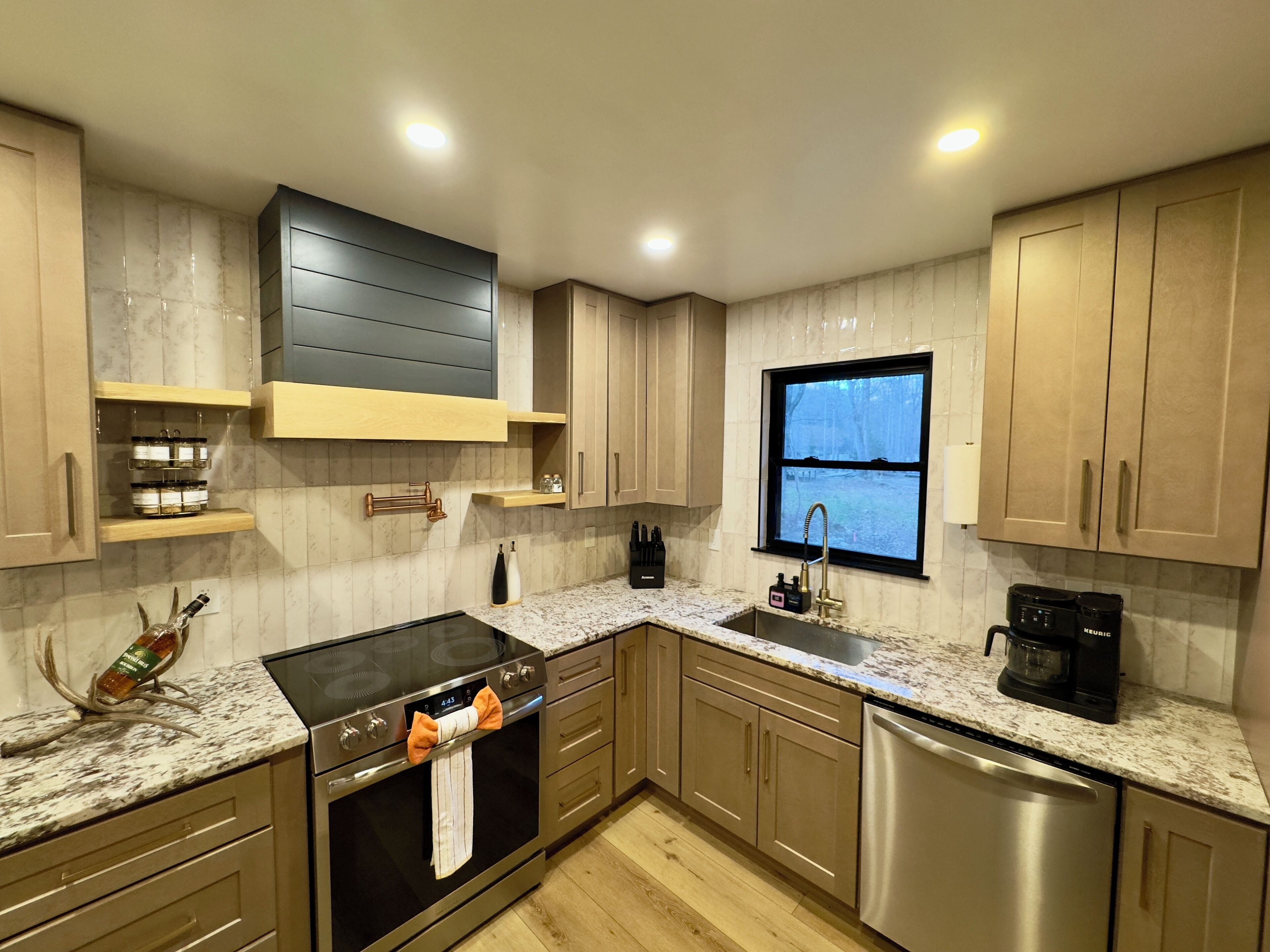 A modern kitchen with a stainless steel dishwasher, oven, and a coffee maker on the counter.