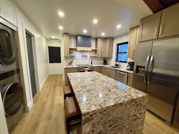 A modern kitchen with a central island, stainless steel appliances, and wooden cabinetry.