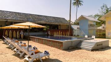 A poolside area with lounge chairs, umbrellas, and a swimming pool.