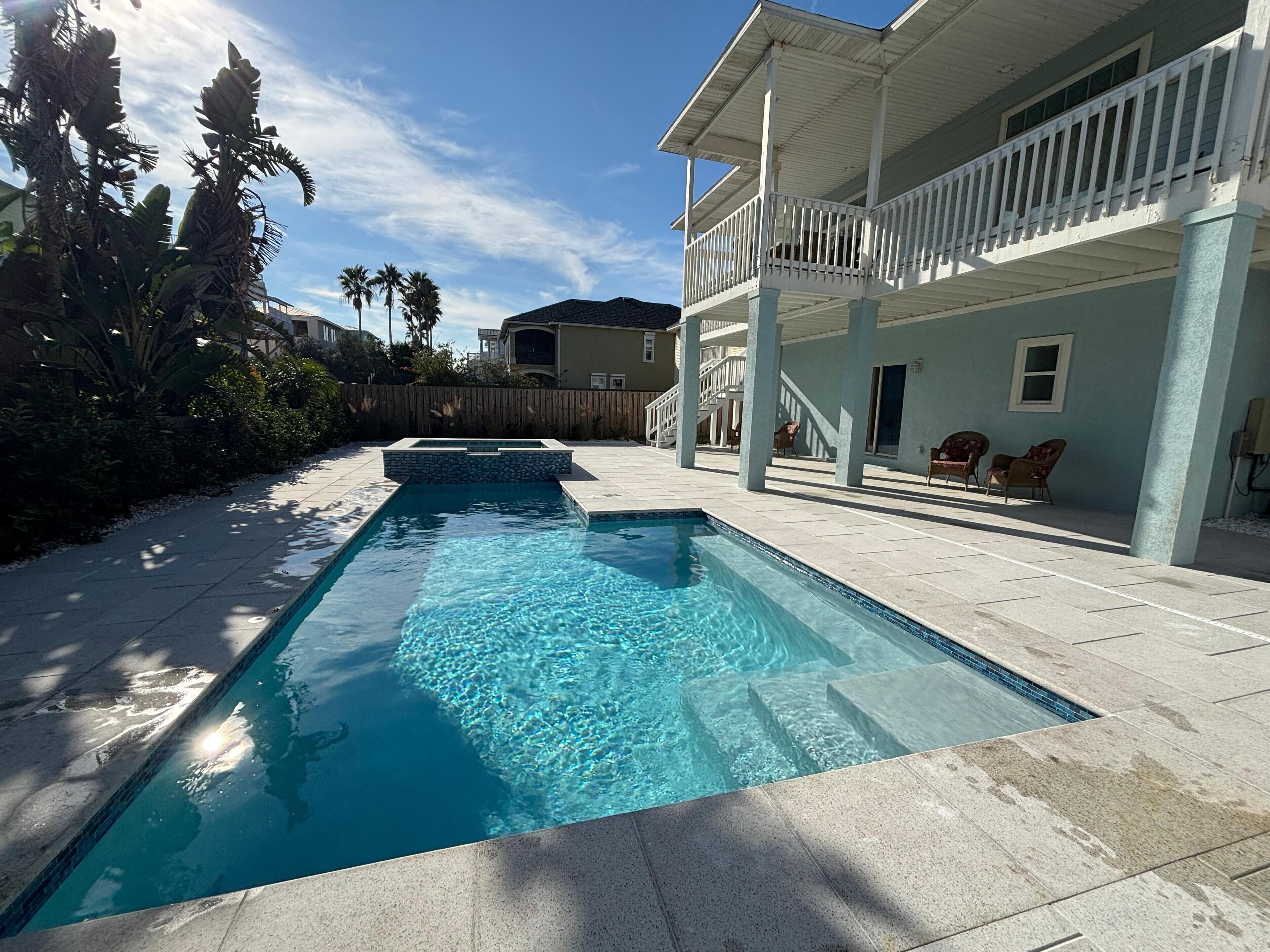 A rectangular swimming pool with clear blue water, surrounded by a tiled patio.