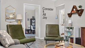 A living room with two green leather chairs, a round coffee table, and a wall with a motivational quote.