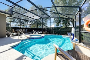 Une piscine extérieure dotée d’une structure en verre, de chaises longues et d’une bouée de sauvetage.