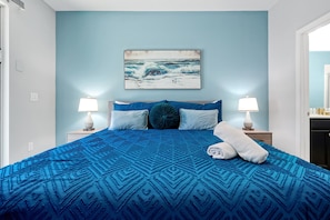 A bedroom with a large bed, two bedside lamps, a painting of waves, and a towel on the bed. - 5-bedroom pool home with spa and Mario game room at Solterra Resort, near Disney (Davenport)