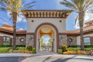 A building entrance with an arched gateway, stone walls, and a tiled roof. - 5-bedroom pool home with spa and Mario game room at Solterra Resort, near Disney (Davenport)