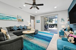 Un salon moderne avec un canapé gris, une table basse ronde et un tapis à motifs bleus.