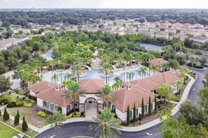 Un quartier résidentiel doté d’une piscine centrale, entourée de palmiers et de maisons.