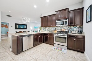 A modern kitchen with dark wood cabinets, stainless steel appliances, and a tiled backsplash. - All the best family comforts at this very popular 5 bedroom home (Davenport)