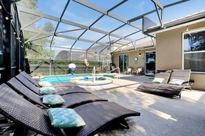 Een overdekt terras met lounge fauteuils en een zwembad.