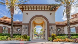 A gated entrance with an arched canopy, stone walls, and palm trees. - All the best family comforts at this very popular 5 bedroom home (Davenport)