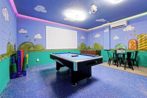 Ein Raum mit Billardtisch, Kicker und einem Tisch mit Stühlen.