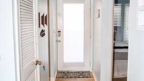 A hallway with a white door, a patterned rug, and a light-colored floor. - Bethany Beach Sea Colony Resort Condo w/Lake Views.   (Bethany Beach)