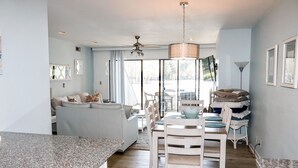 A modern kitchen with granite countertops, a dining area with white chairs, and a large window providing natural light. - Bethany Beach Sea Colony Resort Condo w/Lake Views.   (Bethany Beach)