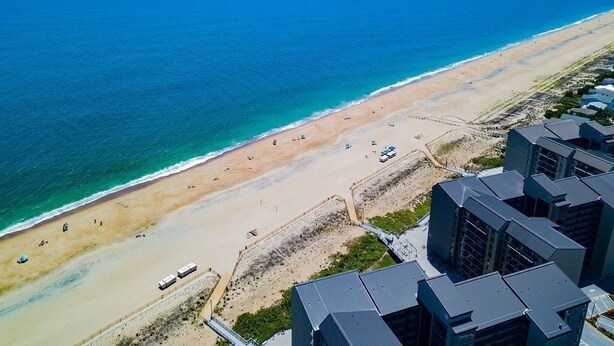 An aerial view of a beach with a row of modern buildings along the shore. - Bethany Beach Sea Colony Resort Condo w/Lake Views.   (Bethany Beach)