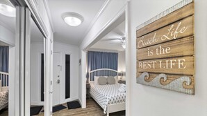 Une chambre à coucher comprenant un lit, une table de chevet, un panneau fixé au mur et un ventilateur de plafond.